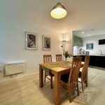 Modern dining room and kitchen with wooden furniture.