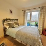 Cosy bedroom with guitar and large window view.