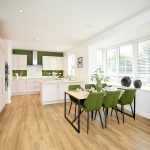 Modern kitchen dining area with green chairs.
