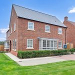 Modern red brick house with garden and driveway.