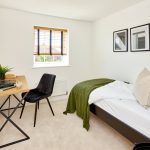 Minimalist bedroom with desk and green accents.