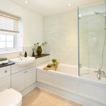 Modern bathroom with white fixtures and glass shower.