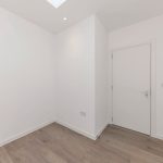 Empty white room with wooden floor and door.