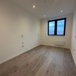 Empty room with wooden floor and window view.