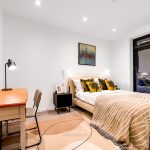 Modern bedroom with desk and decorative cushions.
