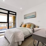 Modern bedroom with balcony, desk, and decor.