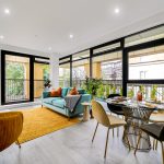 Modern living room with large windows and dining area.