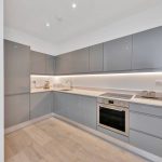 Modern grey kitchen with appliances and wooden flooring.