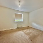 Empty bedroom with carpet and single window.