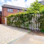 Brick house exterior with garden fence and driveway.