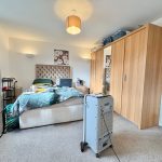 Modern bedroom with bed, wardrobes, and air cooler.