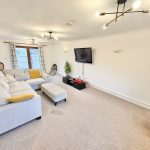 Spacious living room with modern decor and lighting.