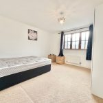 Bright bedroom with bed, carpet, and window.