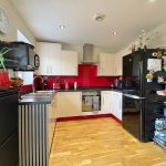 Modern kitchen with red accents and appliances.