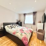 Cosy bedroom with floral bedding and wooden flooring.