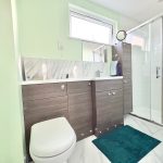 Modern bathroom with green walls and shower.