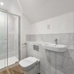 Modern bathroom with shower, toilet, and sink.