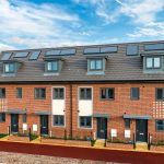 Row of modern brick townhouses with solar panels.