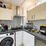 Compact kitchen with modern appliances and white cabinets.