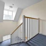 Bright stairwell with window and white banister railing.