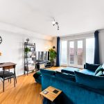 Modern living room with blue sofa and balcony doors.