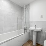 Modern tiled bathroom with bath, shower, sink, toilet.