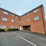 Red brick apartment building with parking area.