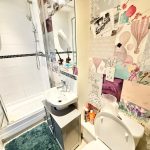 Small bathroom with shower and decorative wallpaper.