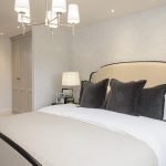 Modern bedroom with grey pillows and chandelier.