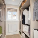 Organised walk-in wardrobe with clothes and shopping bags.