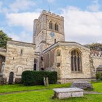 Historic stone church with clock tower and graveyard.