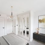 Modern bedroom with mirrored wardrobe and stylish decor.