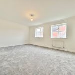 Empty room with grey carpet and windows.