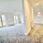 Spacious, carpeted lounge with French doors and hallway.