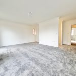 Spacious room with grey carpet and white walls.