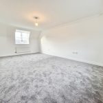 Spacious room with grey carpet and window.