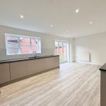Spacious modern kitchen with wood flooring and ample light.