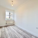 Empty room with wooden floor and large window.