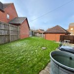 Back garden with green grass and patio view.
