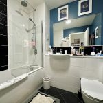 Modern bathroom with shower, sink, toilet, and blue walls.