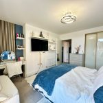 Modern bedroom with stylish decor and large TV.