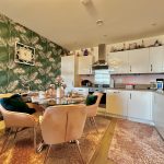 Modern kitchen dining area with green wallpaper.