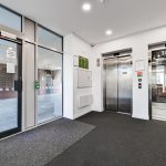Modern building lobby with glass doors and elevators.