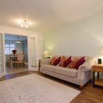 Cosy living room with sofa, table lamp, and dining area.
