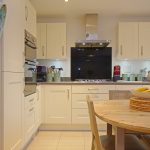 Modern kitchen with cream cabinets and dining table.