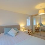 Spacious bedroom with mirrored wardrobe and soft lighting.