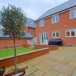 Spacious garden with brick patio and tree.