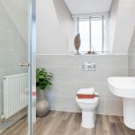 Modern bathroom with toilet, sink, and plant decor.