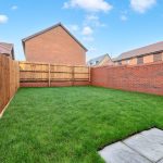 Sunny fenced garden with lawn and patio.