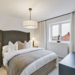 Modern cosy bedroom with double bed and white curtains.